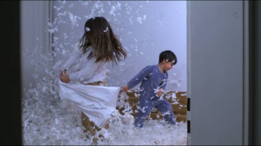 Çocukların yastık savaşı yaptığı mutlu bir an. Tüyleri havada uçuşuyor. Yavaş çekimde.