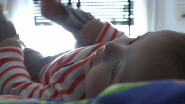 Bebek yatakta ayakla oynuyor.