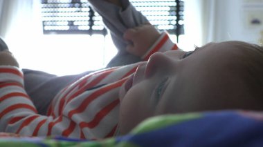 Bebek yatakta ayakla oynuyor.