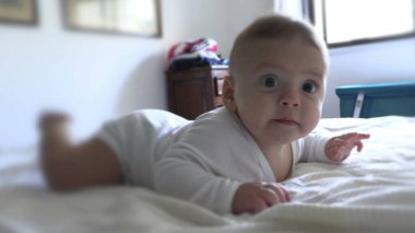 Sevimli bebek, sabah uyanıp yatakta eğleniyor.