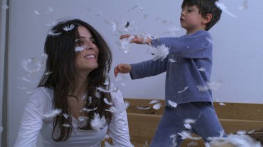 Anne ve çocuklar 1000 fp hızla çok yavaş çekimde havaya tüy fırlatıyorlar. Yastık savaşı sonrası çocuklarla kaynaşan kadın tüyü her yere düşüyor.