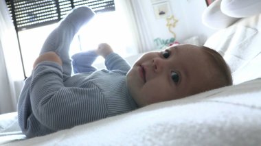 Bebek yatağa uzanmış kameraya bakıyordu.