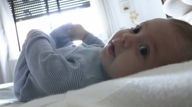 Tatlı, tatlı bebek yatakta uzanmış kameraya bakıyor.
