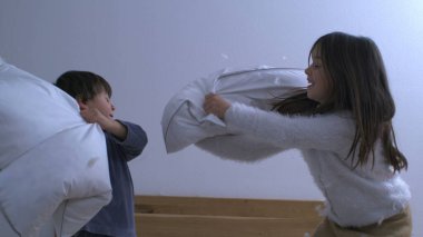 Sevimli Küçük Oğlan ve Yastık Savaşındaki Tatlı Küçük Kız, Kardeşler Yastıklarla Eğleniyor, Tüyler uçuşuyor.