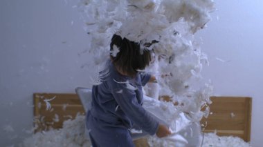 Havada uçuşan tüylerle yastık savaşı yapan eğlenceli çocuklar, yüksek hızlı yavaş çekim kamerasıyla yakalanan çocukların tasasız oyunları.