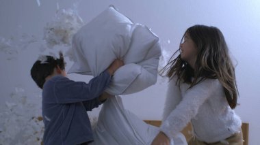 Sevimli Küçük Oğlan ve Yastık Savaşındaki Tatlı Küçük Kız, Kardeşler Yastıklarla Eğleniyor, Tüyler uçuşuyor.