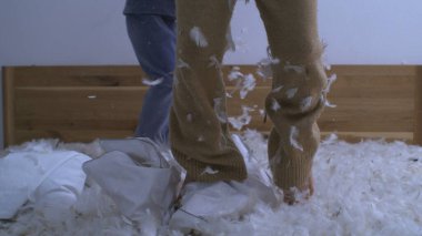 Yatakta zıplayan neşeli çocuklar yüksek hızlı kamerayla 1000 fps hızla çekiliyorlar. Tüylerle kaplı küçük kız hoplayıp zıplarken