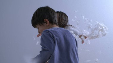 Ultra Slow Motion yastık savaşı - Çocuklar Yatakta Ayakta Duruyor, Tüyler 1000 FPS 'de uçuyor. Küçük çocuk kız kardeşine yastık fırlatıyor.