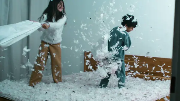 Pillow Fight Excitement - Sister Battling Small Brother, Feathers Flying in Speed