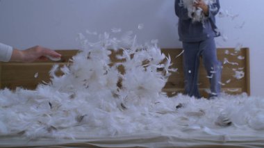 Yatak yüzeyinde tüyler uçuşuyor ve arka planda duran çocuk yavaş çekimde çekiliyor.