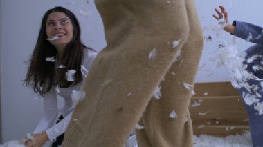 Aile yastık savaşı yapıyor ve tüyleri havada yavaş çekimde 1000 fp hızla uçuyor. Anne çocuklarla oynarken tüy atıyor.