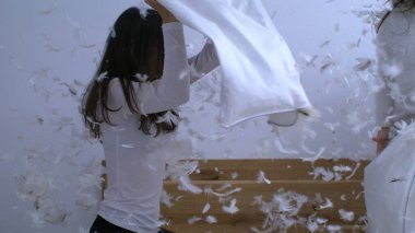 Anne ve çocuğun yastık savaşı oynadığı mutlu an. Süper yavaş çekimde havada uçuşan tüylerle 1000 fps hızla yakalanan çocuklarla.