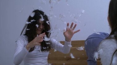 Kadın yastık savaşı sonrası çocuklarla oynarken çok yavaş çekimde havaya tüy atıyor. Otantik aile mutlu anı