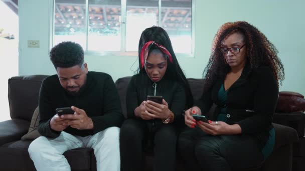 Три Человека Смотрят Свои Телефоны Сидящие Диване Помещении Загипнотизированные Технологией — стоковое видео