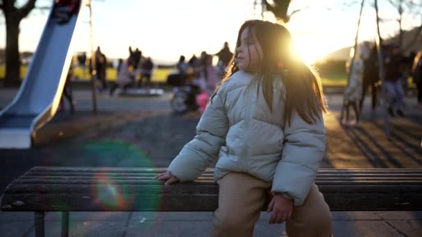 Одна Созерцательная Маленькая Девочка Сидящая Скамейке Парке Пальто Время Зимнего — стоковое видео
