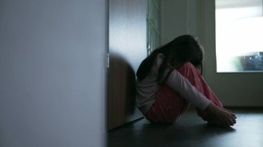 Zorlanan çocuk koridorda oturuyor yüzünü kapatıyor zor zamanlarda yalnızlık ve yalnızlık hissediyor. Çocukluk depresyonu