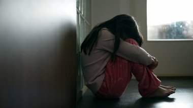 Korkmuş küçük kız endişeli yüzünü kapatıyor, çocuk koridorda yalnız ve üzgün hissediyor.