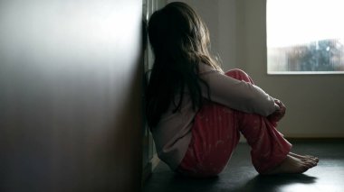 Korkmuş küçük kız endişeli yüzünü kapatıyor, çocuk koridorda yalnız ve üzgün hissediyor.