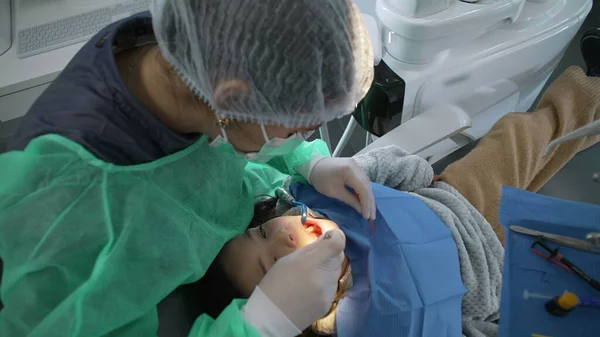 Dentist at work - Female dental doctor providing professional help to child seated seen from overhead