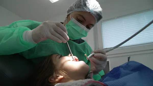 Focused Female Dentist Treating Patient's Oral Health in Clinic