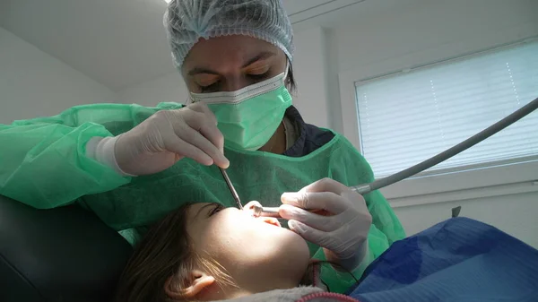 Focused Female Dentist Treating Patient's Oral Health in Clinic