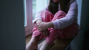 Çocuk Evde Yalnız Hissediyor, Çocuklukta Zorluklarla Mücadele Ediyor. Apartman penceresinden bakan küçük bir kız, düşüncelere dalmış, üzgün ve depresif.