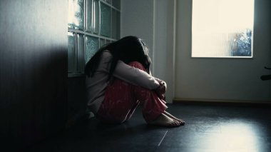 Evde koridorda otururken yüzünü kapatan yalnız bir çocuk. Çocukluğunda akıl hastalığıyla boğuşan yalnız küçük bir kızın dramatik sahnesi.