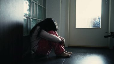 Evde koridorda otururken yüzünü kapatan yalnız bir çocuk. Çocukluğunda akıl hastalığıyla boğuşan yalnız küçük bir kızın dramatik sahnesi.