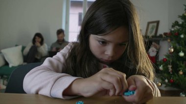 Konsantre küçük kız oyuncağını monte ediyor. Bayan çocuk nesneleri bir araya getiriyor. Kendi kendine oyun oynuyor. Çocukluk eğlencesi aktivitesi.