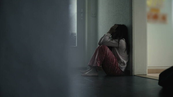 Дети борются с психическими заболеваниями в детстве, сидят в темном коридоре, закрывая лицо в тревоге