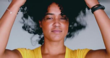 Kıvırcık saçlarıyla oynayan Afro-Amerikalı genç bir kadın kameraya bakıyor. 20 'li yaşlarda Brezilyalı bir kız yakın plan saç portresi yaptırıyor.