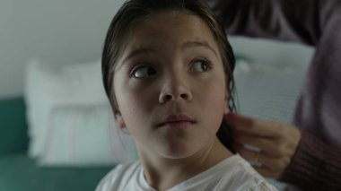 Anne ve babası gece yatmadan önce çocukların saçlarını tarıyor. Anne saçlarını tararken küçük kızın yüzünü yakından tarıyor.