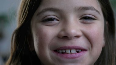 Kameraya gülümseyen neşeli, küçük bir kız. Çocuk portresi, çocukluk mutluluğu.