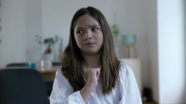 İnançsızlıkla kendini işaret eden küçük bir kız sonra da suçlamayı reddeden parmağını sallıyor. Çocuk sözsüz jesti onaylamıyor