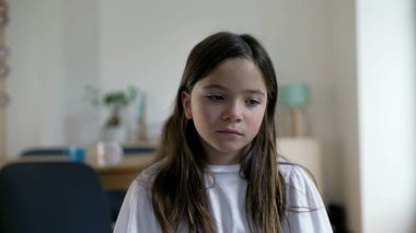 Üzgün, düşünceli, düşünceli bir yüzü olan küçük bir kız. Evde derin zihinsel yansıması olan çocuk portresi