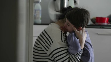 Anne teselli ediyor ağlayan küçük çocuk, şefkatli ebeveynin samimi bir anında üzgün çocuğa empatik bir şekilde sarılıyor zorluklarla, otantik ve gerçek hayatta mücadele ediyor.