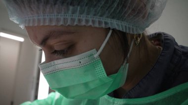 Yakın plan kadın dişçi işe odaklanmış, antiseptik kıyafetler giyiyor. Derin odaklı diş hekimi, makro yakın plan profil yüzü