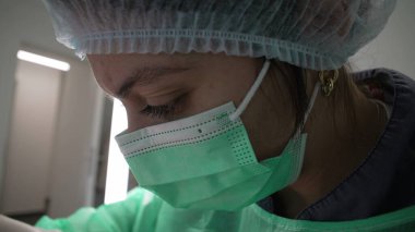 Yakın plan kadın dişçi işe odaklanmış, antiseptik kıyafetler giyiyor. Derin odaklı diş hekimi, makro yakın plan profil yüzü