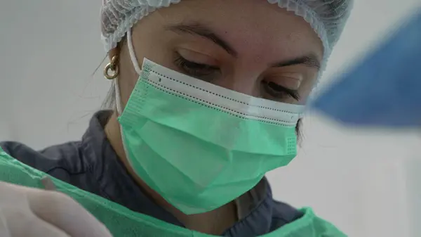 Focused Female Doctor's Face While Performing Surgical Procedure
