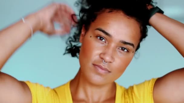 ブラジルの黒人大人の少女が カメラを見ながら髪を調整している アフリカ系アメリカ人の若い女性は カーリーヘアスタイルでクローズアップフェイスプレイを取得 — ストック動画