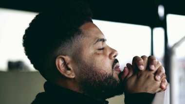 Umutlu genç adam gözleri kapalı ve elleri birbirine kenetlenmiş bir şekilde Tanrı 'ya dua ediyor. Sadık ve Ruhsal profil yakın plan yüzü