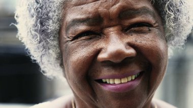 80 'lerdeki yaşlılığı resmeden kameraya gülümseyen siyahi bir kadının karizmatik portresi. Arkadaş canlısı, mutlu, yaşlı, kırışık ve gri saçlı Afrikalı Amerikalı.