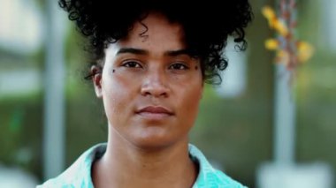 Genç, kendinden emin bir zenci kadın kameraya doğru yürüyor. Afrika kökenli 20 'li yaşlarda, kıvırcık saçlı bir kadının yakın çekim görüntüsü.