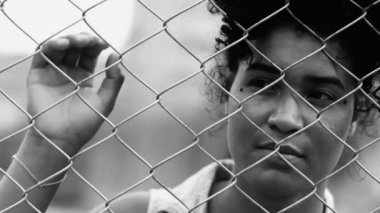 Depresyondaki genç Afrikalı Amerikalı kadın metal çitlere yaslanıyor umutsuz ve umutsuz hissediyor dramatik monokromda, siyah ve beyaz