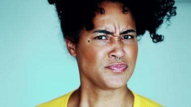 Öfkeli genç siyah bir kadın başını sallıyor kameraya bakarken hoşlanmadığı bir şey gösteriyor, yakın plan yüz resmi.