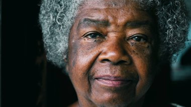 Ciddi bir siyahi yaşlı kadın kamera karşısında deneyimli ve bilge görünüyor. Kırışıklıkları ve gri saç portresi olan 80 'li yaşlarda Afro-Amerikalı bir kadın.