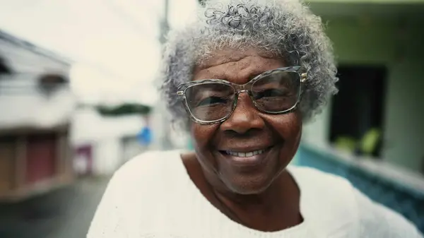 Portrait of Joyful 80s African Descent Senior Woman with Gray Hair on Balcony, close-up of South American elderly gray hair elderly person with friendly grin