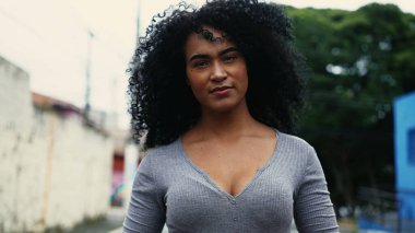 Kenar mahallede kıvırcık saçlı, kendinden emin, genç bir Brezilyalı kadın yürüyor. 20 'li yaşlarda Latin kökenli yetişkin bir kız kentte geziniyor. Kendini güvende ve kendinden emin hissediyor.