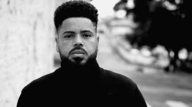 Ciddi bir siyah adam ciddi bir ifadeyle Kentsel caddede yürüyor. 20 'li yaşlarda Güney Amerikalı siyah-beyaz, tek renkli...