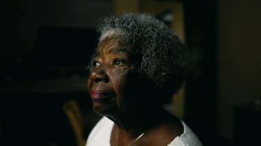 Derin düşüncelere dalmış gri saçlı, yaşlı, meditasyon yapan yaşlı Afrikalı Amerikalı kadın. Evde tek başına oturan siyahi yaşlı bir kadın.